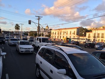 Cars on city street against sky