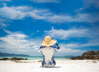 Rear view of woman standing on beach against sky