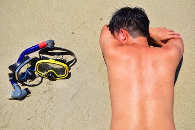 Rear view of shirtless man lying on sand