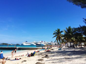 People on beach against clear blue sky