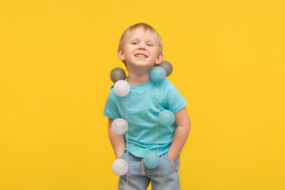 Portrait of smiling girl standing against yellow background