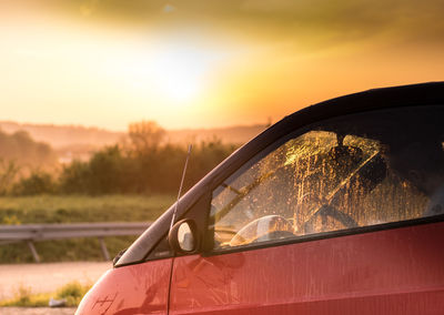 Close-up of orange car against sky at sunset