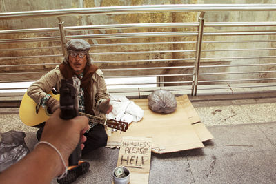 Man holding cigarette while sitting outdoors