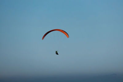 Low angle view of person paragliding against clear blue sky