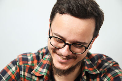 Smiling man wearing eyeglasses and a checkered shirt, with black hair, white background 