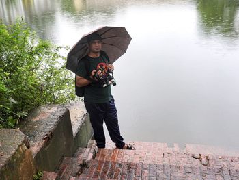 Full length of woman photographing while standing by lake