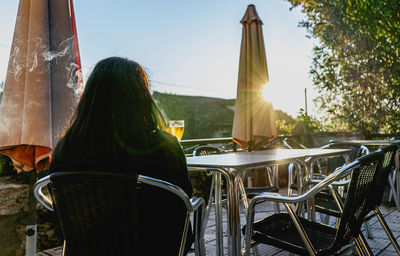 Person sitting on a terrace of a bar with a glass of beer