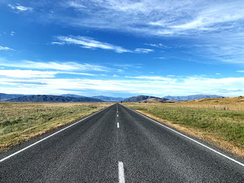 Road leading to distant hills landscape against sky