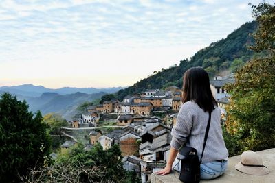 Rear view of woman looking at mountain against sky