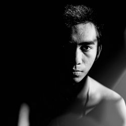 Portrait of young man against black background