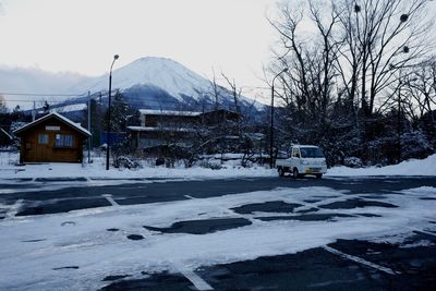 Houses by road against sky during winter
