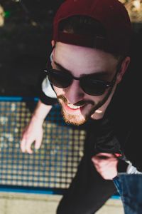 High angle view of young man wearing sunglasses sitting outdoors