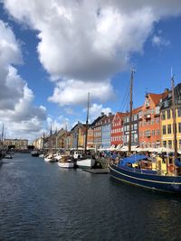 Sailboats moored on river by buildings in city against sky