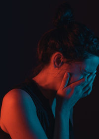 Portrait of young woman against black background