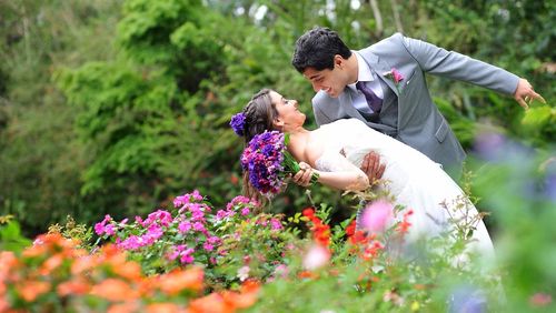 Groom holding bride while standing at garden