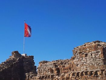 Low angle view of flag on building against blue sky