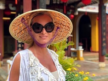 Portrait of woman in hat standing at temple