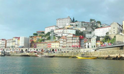 Buildings by river against sky in city