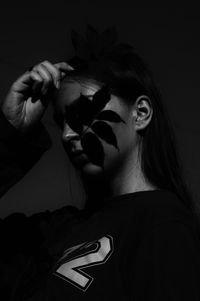 Portrait of young woman against black background
