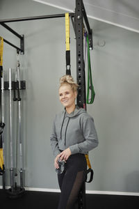 Smiling woman standing in gym and holding water bottle