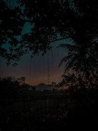 Silhouette trees by lake against sky during sunset