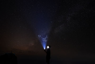 Low angle view of silhouette man standing against star field at night