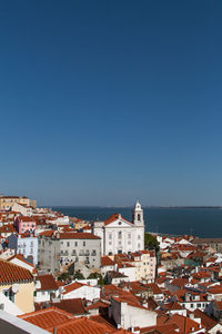 High angle view of town by sea against blue sky