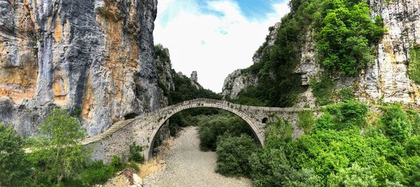 Arch bridge amidst trees against sky