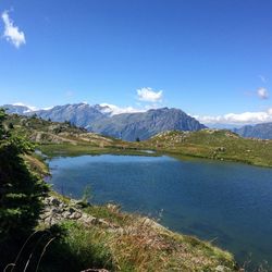 Scenic view of lake and mountains against blue sky at huez