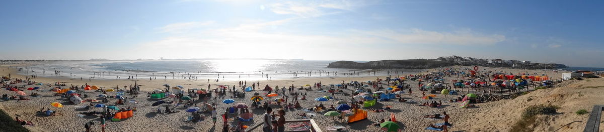 Panoramic view of people at beach against sky