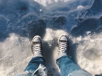 Low section of man standing on frozen lake