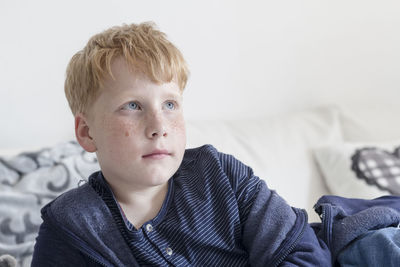 Boy looking up while lying on bed at home