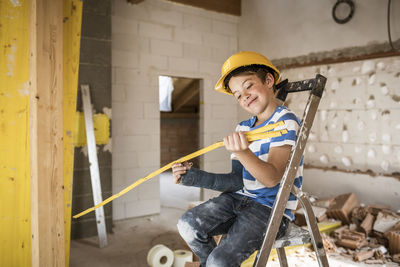 Portrait of smiling boy holding umbrella against wall