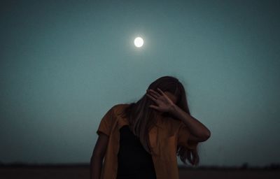 Woman standing against moon in sky