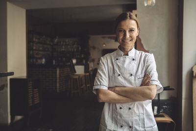 Portrait of smiling chef with arms crossed in restaurant