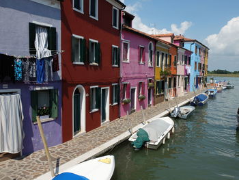 Boats moored in canal by building against sky