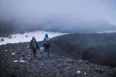 Rear view of men walking on mountain road