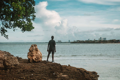 Rear view of man walking on beach against sky