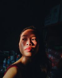 Close-up of woman looking away in dark