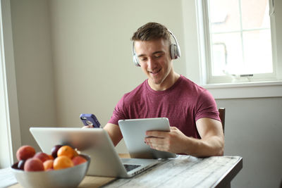 Young man using mobile phone while sitting on table