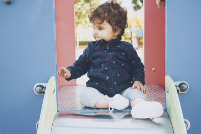 Boy sitting near slide in playground