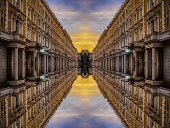Reflection of buildings in puddle on street against sky