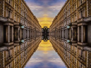 Reflection of buildings in puddle on street against sky