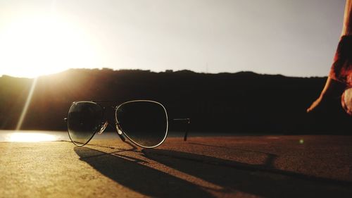 Close-up of sunglasses on beach during sunset
