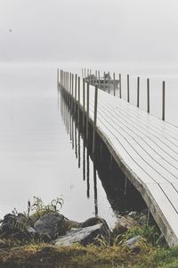 Empty pier over lake against sky