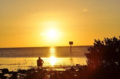 Silhouette beach against sky during sunset