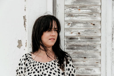 Portrait of beautiful young woman standing against wall