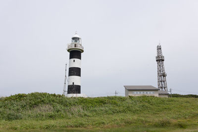 Looking up at the black and white lighthouse under cloudy skies