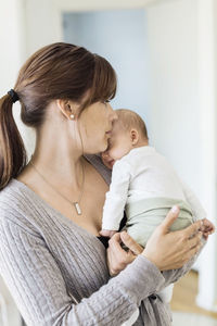 Mid adult woman carrying baby girl at home