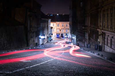 Light trails on city street by buildings at night